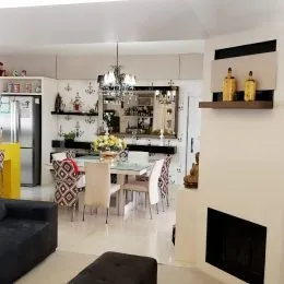 Imagem de uma sala de estar com mesa de jantar e armários brancos.