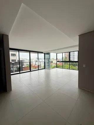 Sala ampla com grandes janelas de vidro que oferecem uma vista externa.