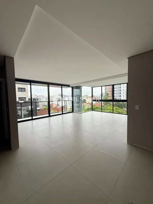 Sala ampla com grandes janelas de vidro que oferecem uma vista externa.
