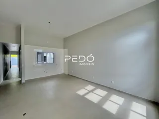 Ambiente interno de uma sala ampla com piso claro e paredes brancas.