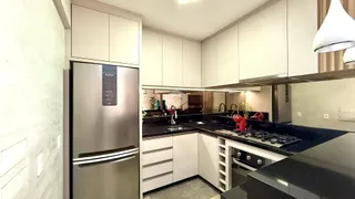 Cozinha moderna com armários brancos e bancadas escuras.