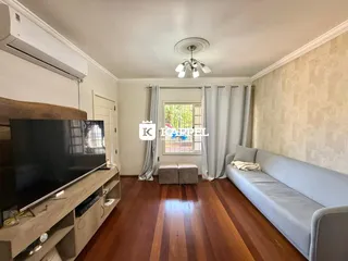 Sala de estar com sofá e televisão em piso de madeira.