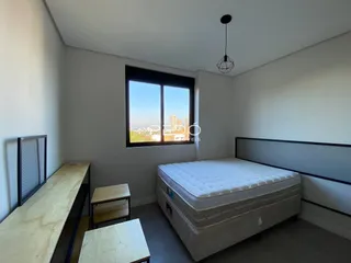 Quarto com vista para a paisagem urbana através de uma grande janela.