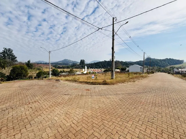 Vista externa de um terreno em Lajeado, Brasil, com vegetação e estruturas ao fundo.