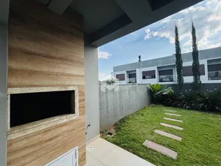 Vista da fachada de uma residência com jardim e árvores altas.