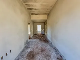 Corredor longo com paredes brancas e piso áspero.