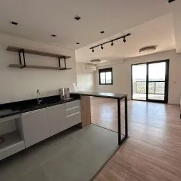 Sala de estar com bancada escura e piso de madeira clara.