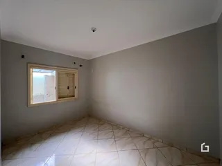 Ambiente interno com piso de cerâmica claro e janela com venezianas de madeira.