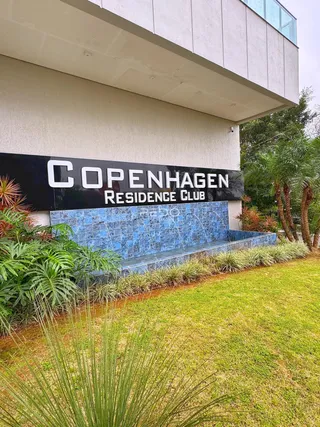 Fachada de um clube residencial em Lajeado, Brasil, com jardim bem cuidado.