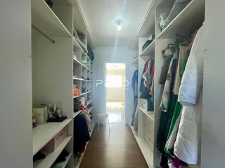Hall de entrada com estantes e roupas em um imóvel.