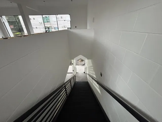 Corredor interno com paredes brancas e piso escuro.