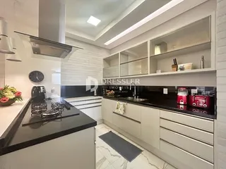 Uma cozinha moderna com armários brancos e bancadas escuras.