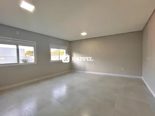 Uma sala de estar ampla com paredes cinzas e piso claro.