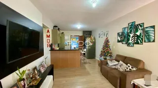 Sala de estar com televisão e área de cozinha ao fundo.