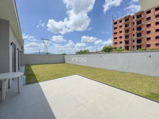 Vista externa de um quintal com gramado e muro de vedação.