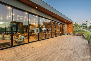 Fachada moderna de um imóvel com grandes janelas de vidro e deck de madeira.