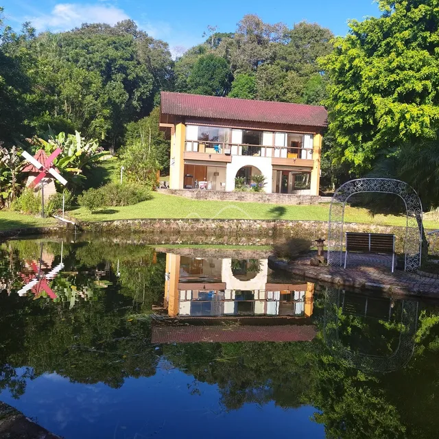 Vista externa de uma casa com telhado vermelho refletida em um lago em Lajeado, Brasil.
