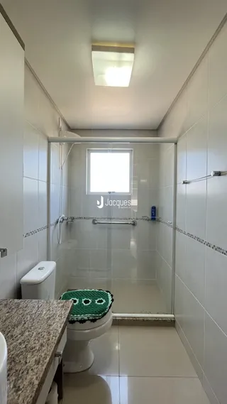 Foto de um banheiro com revestimento cerâmico e box de vidro.
