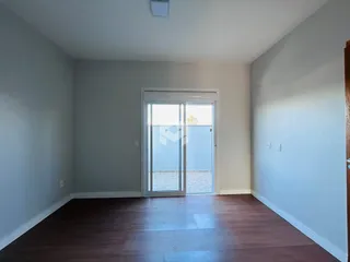 Ambiente interno de uma sala com piso de madeira e porta de vidro.