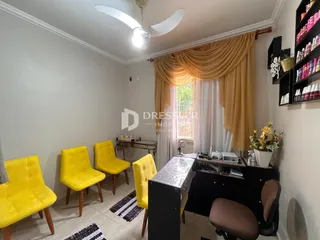 Ambiente interno com cadeiras amarelas e janela com cortinas na residência.