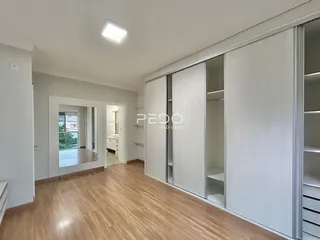 Ambiente interno de uma sala com piso de madeira clara e armários embutidos.