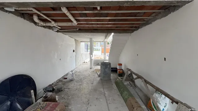 Corredor interno com teto de madeira exposto e paredes brancas.