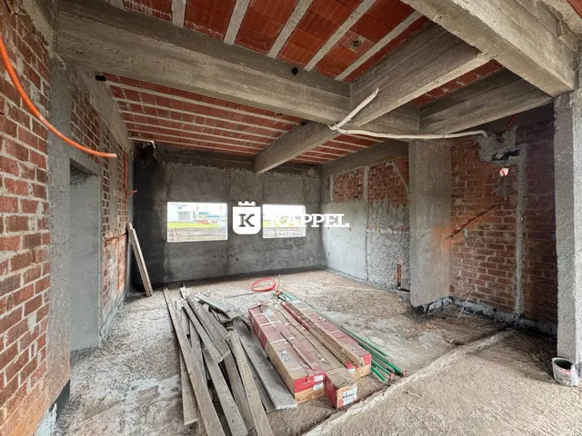 Uma sala em construção com vigas de concreto expostas e paredes de tijolo.