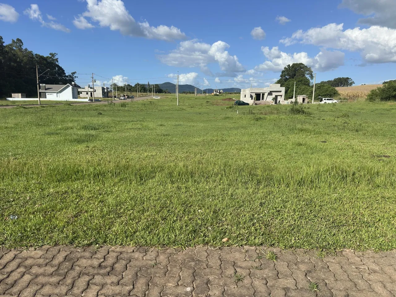 Vista externa de uma propriedade com campo gramado e construções ao fundo.