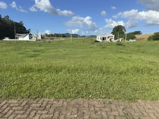 Vista externa de uma propriedade com campo gramado e construções ao fundo.