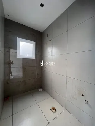 Vista de um corredor com paredes e piso revestidos de cerâmica.