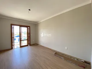 Ambiente interno de uma sala com piso de madeira e porta de vidro em um imóvel em Lajeado.