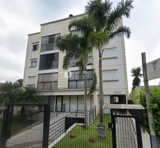 Fachada de um prédio residencial em Lajeado, Brasil, com cerca e vegetação.