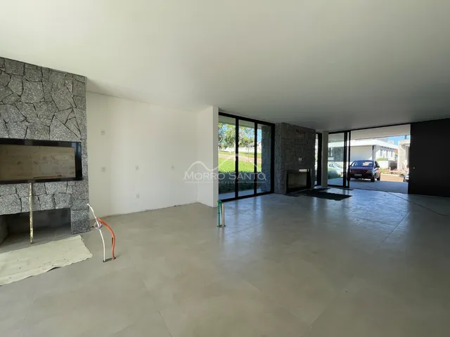 Ambiente amplo com piso de porcelanato e parede de pedra na sala de estar.