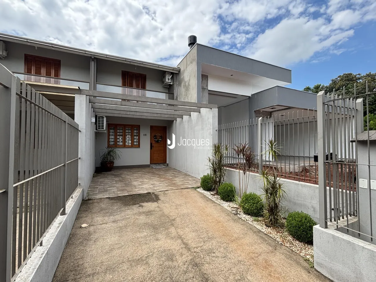 Fachada de uma residência moderna em Lajeado, Brasil, com cerca e paisagismo.