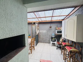 Interior de uma sala com teto de telha exposto e piso de cerâmica.