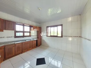 Interior de uma cozinha com armários de madeira e piso de cerâmica branca.