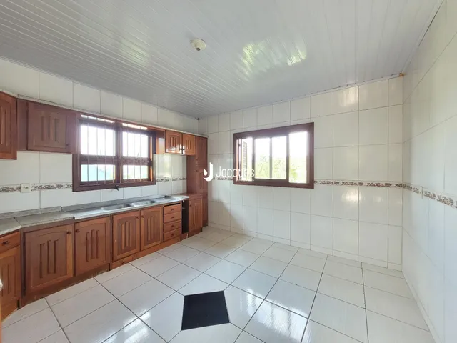 Interior de uma cozinha com armários de madeira e piso de cerâmica branca.