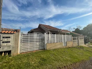 Foto da fachada de uma casa em Lajeado, Brasil, com cerca branca e gramado.
