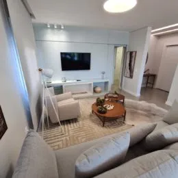 Sala de estar com sofá claro e paredes brancas em um imóvel.