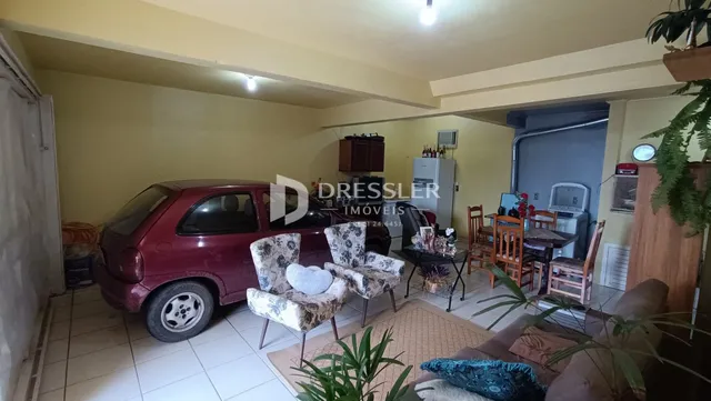 Sala de estar com um carro estacionado no interior de uma residência.