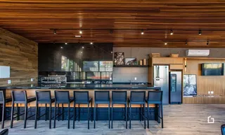 Imagem de uma cozinha moderna com bancada escura e piso de madeira.