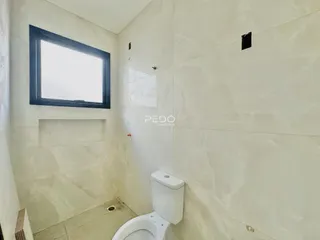 Foto de um banheiro com revestimento de azulejo claro e janela.
