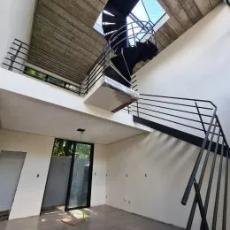 Foto de um corredor interno com escadaria metálica e teto inclinado.