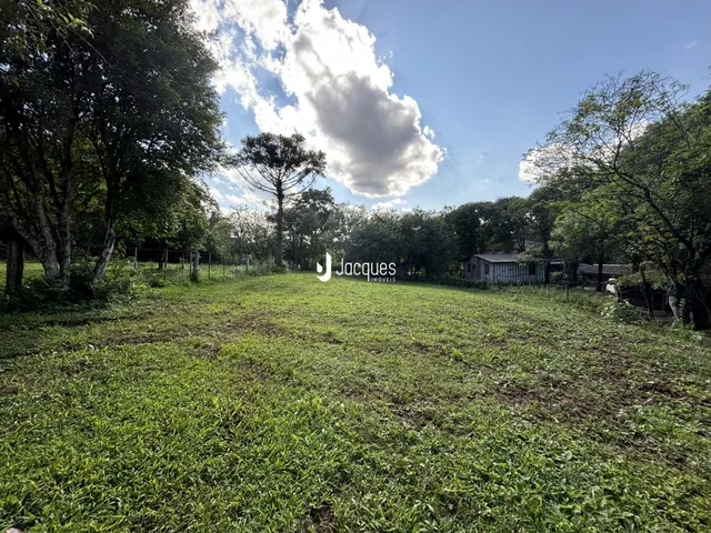 Campo gramado cercado por árvores sob um céu nublado.