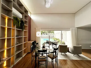 Sala de jantar com mesa de vidro e cadeiras em um ambiente iluminado.