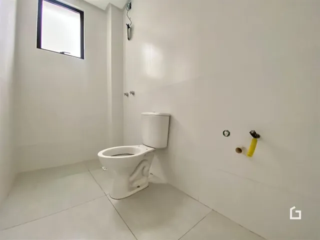 A foto mostra um banheiro com azulejos brancos e uma janela.