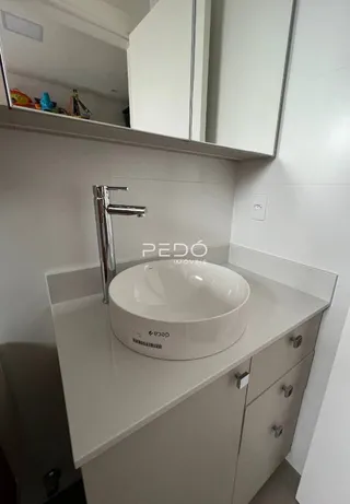 Banheiro com bancada e pia brancas.