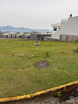 Vista externa de uma propriedade em Lajeado, Brasil, mostrando um terreno gramado em frente a um edifício branco.