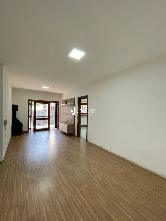 Ambiente interno de uma sala com piso de madeira clara e paredes brancas.