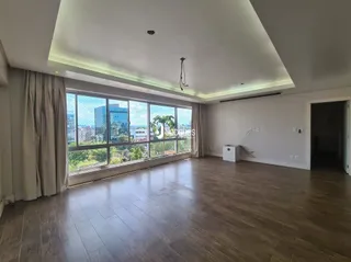 Sala de estar com piso de madeira e grandes janelas que dão vista para o exterior.